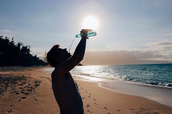 Touriste qui boit de l'eau sur une plage de Guadelouep